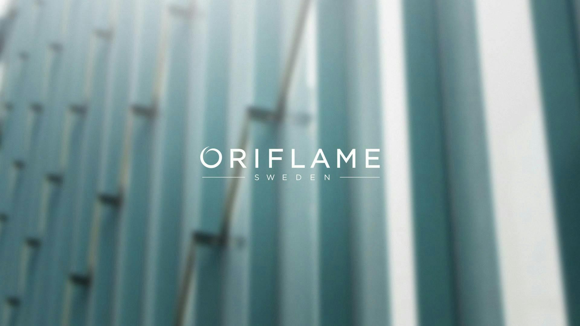 Oriflame-logotyp med byggnad i bakgrunden.